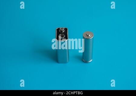 9-V-Hochvolt-Batterie und AA-Alkali-Mangan-Batterie auf blauem Hintergrund. Energie. Stockfoto