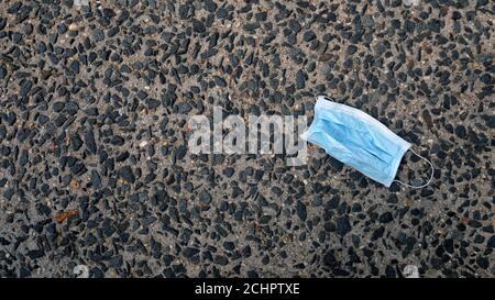 Blaue Einweg-FASK-Maske auf dem Boden entsorgt Stockfoto