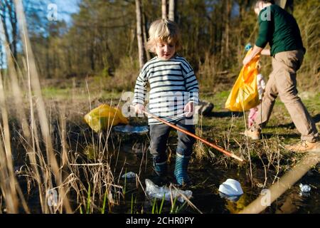 Vater mit kleinen Kindern sammeln Müll im Freien in der Natur, plogging Konzept. Stockfoto