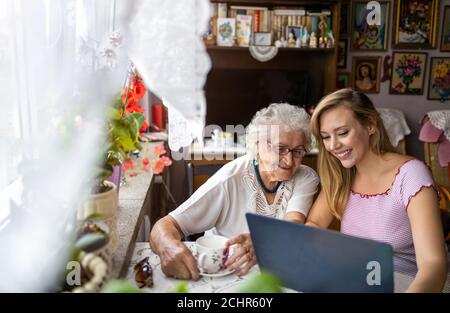 Erwachsene Enkelin lehrt ihre ältere Großmutter, Laptop zu verwenden Stockfoto