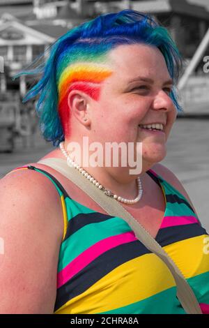 Zoe fügt im September im Pier Approach, Bournemouth, Dorset UK, einen Farbtupfer mit regenbogenfarbenen Haaren und Kleid hinzu Stockfoto