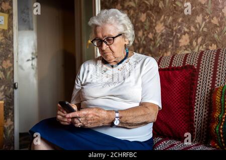 Ältere Frau mit Handy zu Hause Stockfoto