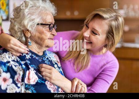Junge Frau verbringt Zeit mit ihrer älteren Großmutter zu Hause Stockfoto