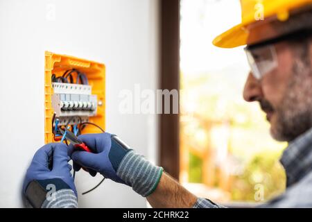 Elektriker bei der Arbeit bereitet elektrische Kabel in der Schalttafel einer elektrischen Wohnanlage vor. Bauindustrie. Stockfoto