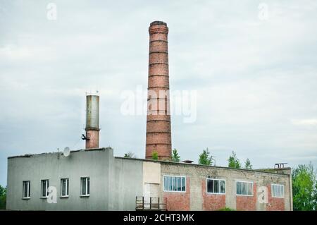 Altes Fabrikgebäude, alte Ziegelrohre aus dem Kesselraum, junge Bäume auf dem Dach, aber mit Fiberglas-Fenstern Stockfoto