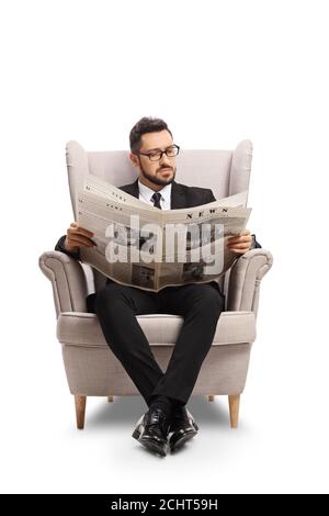 Professioneller Mann in einem schwarzen Anzug, der in einem Sessel sitzt Lesen einer Zeitung isoliert auf weißem Hintergrund Stockfoto