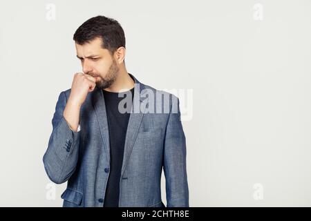 Männliche Geschäftsmann mit einem Bart, sieht angespannt und nervös mit seinen Händen auf dem Mund beißen seine Nägel. Angstproblem. Porträt eines Mannes auf grauem Hintergrund. Stockfoto