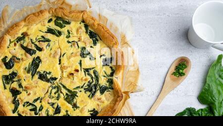 Quiche gefüllt mit Huhn, Mangold mit Holzlöffel auf weichem Hintergrund. Stockfoto