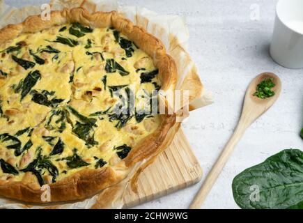 Quiche gefüllt mit Huhn, Mangold mit Holzlöffel auf weichem Hintergrund Stockfoto