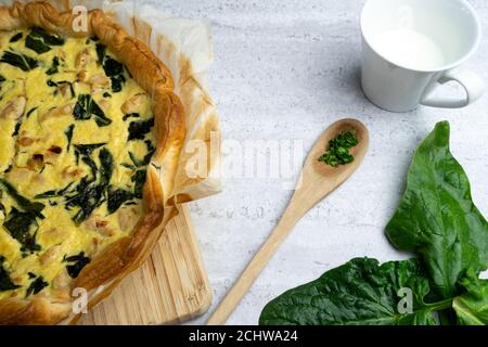 Quiche gefüllt mit Huhn, Mangold mit Holzlöffel auf weichem Hintergrund Stockfoto