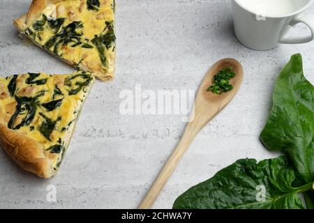 Quiche gefüllt mit Huhn, Mangold mit Holzlöffel auf weichem Hintergrund Stockfoto