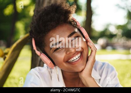 Glücklich junge afroamerikanische Mädchen, Musik mit Wireless hören Kopfhörer im Freien Stockfoto