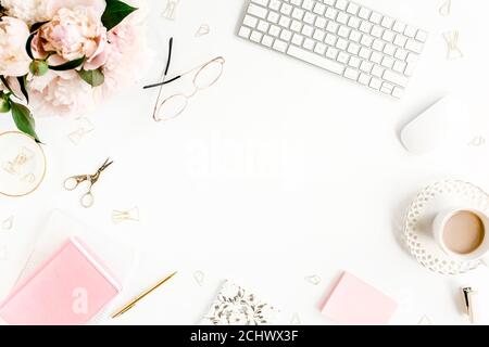 Flacher Schreibtisch für Damen. Weiblicher Arbeitsplatz mit Computer, rosa Pfingstrosen Bouquet, Accessoires auf weißem Hintergrund. Draufsicht femininer Hintergrund. Stockfoto