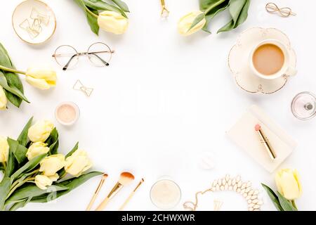 Weiblicher Arbeitsplatz mit gelben Tulpenblüten, Damenmode goldene Accessoires, Tagebuch, Gläser auf weißem Hintergrund. Flach liegend. Feminine Draufsicht. Stockfoto