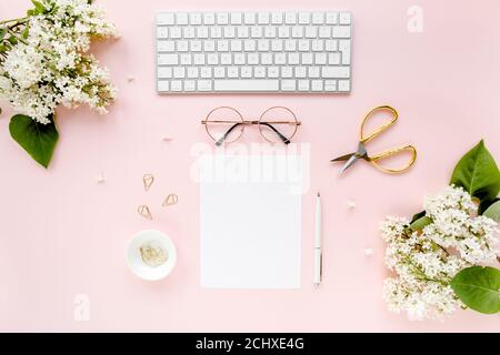 Arbeitsplatz mit Computer, Blumenstrauß Flieder, Zwischenablage. Damen Mode Accessoires isoliert auf rosa Hintergrund. Flach liegend. Schreibtisch mit Blick von oben. Stockfoto