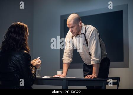 Ein frech Typ, der eines Verbrechens verdächtigt wird, zerreißt Dokumente während eines Verhörs vor einem Ermittler. Stockfoto