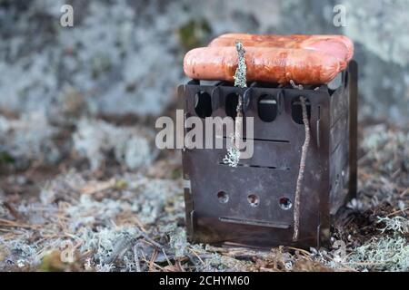 Die Wurst wird auf einem Feuer im Wald gebraten Stockfoto