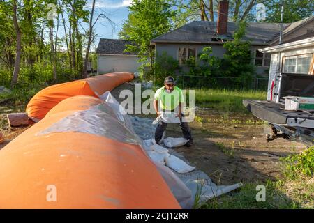 Detroit, Michigan - EIN Arbeiter setzt Sandsäcke, um einen orangen "Tiger Dam" nahe einem Kanal zu stützen, der zum Detroit River und den großen Seen verbindet. Das p Stockfoto