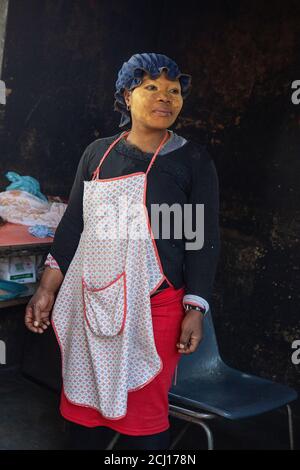 Afrikanische Frau trägt Gesichtsfarbe auf Shisanyama (Grill) Stand, Südafrika Stockfoto