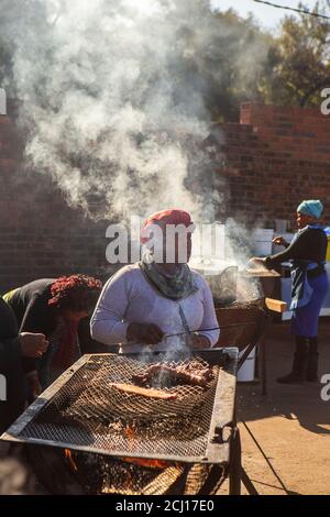 Afrikanische Frau Kochen Shisa Nyama Feuergrill auf dem Markt in Township, Johannesburg, Südafrika Stockfoto