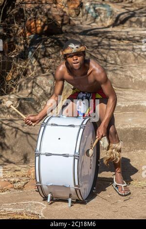 Zulu Mann in traditioneller Kleidung, der die Trommel spielt Stockfoto