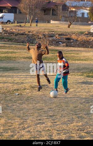 Afrikanische Jungen spielen ein Fußballspiel (Fußball) in einem Park in Soweto Township, Südafrika Stockfoto