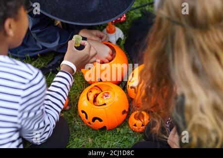 High-Angle-Ansicht auf Gruppe von Kindern tragen Kostüme nehmen Süßigkeiten aus Halloween Eimer im Freien, kopieren Raum Stockfoto