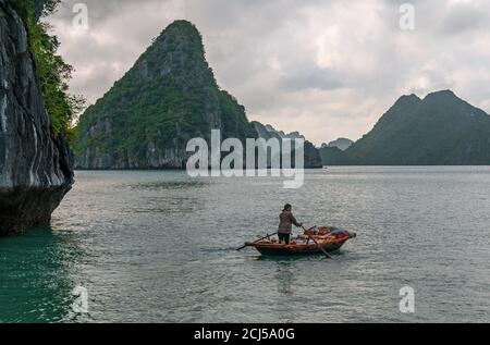 Vietnamesische Verkäuferin auf traditionellem Boot zwischen dem Karst von Halong Bay, Südchinesisches Meer, Nordvietnam. Stockfoto