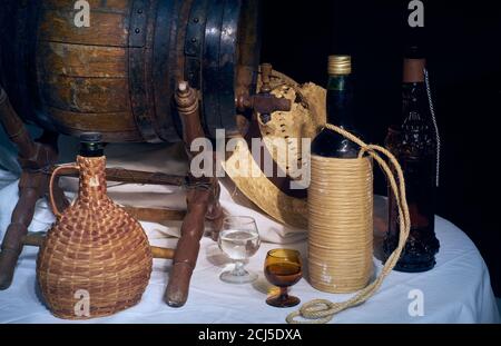 Stillleben mit altem Eichenfass, Flaschen und Smiley auf schwarzem Hintergrund. Stockfoto