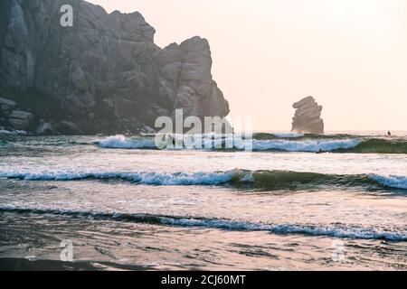 Morro Bay State Park, Kalifornien/USA - 13. September 2020. Surfen in Marro Bay bei Sonnenuntergang, kalifornische Küste. Stürmischer Ozean und berühmter Marro Rock Stockfoto