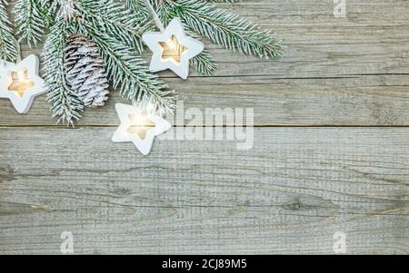 Verschneite weihnachtsbaum Zweig und Sterne Lichter Girlande auf natürliche Holzhintergrund Stockfoto