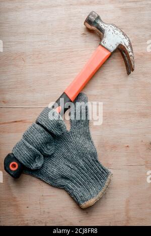 Schutzhandschuhe für den Arbeiter, der Hammer auf dem Holz hält Tabelle Stockfoto