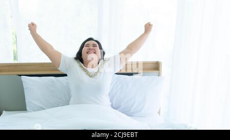 Frauen plus Größe wachen auf und Glück auf dem Bett Zimmer Stockfoto