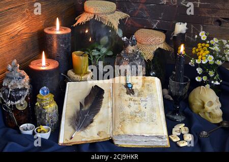 Stillleben mit Zauberbuch, magische Gläser mit Pflanzen und Trank auf Hexentisch. Esoterischer, gotischer und okkulter Hintergrund, Halloween mystisches Konzept. Stockfoto