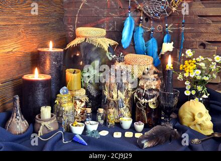 Stillleben mit magischen Flaschen mit Tränke und Kräutern, Runen, schwarzen Kerzen und Totenkopf auf Hexentisch. Esoterischer, gotischer und okkulter Hintergrund, Halloween Stockfoto