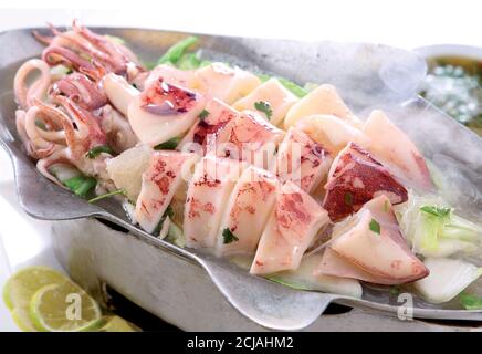 Frisch Raw Tintenfisch auf Schneidebrett mit Salat Gewürze Zitronenlibl, frische Tintenfische Oktopus oder Tintenfisch für gekochte Lebensmittel im Restaurant oder Meeresfrüchte-Markt, L Stockfoto