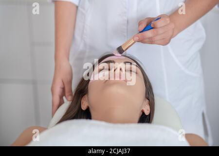 Gesichtsmaske. Kosmetologe Anwendung Ton Gesichtsmaske auf Frauen Gesicht Stockfoto