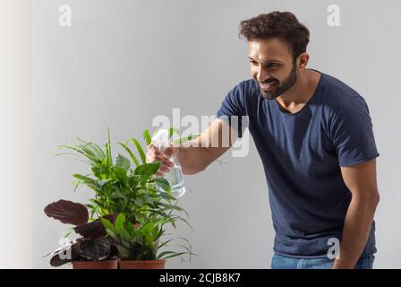 Junger Mann wässern seine Pflanzen zu Hause Stockfoto