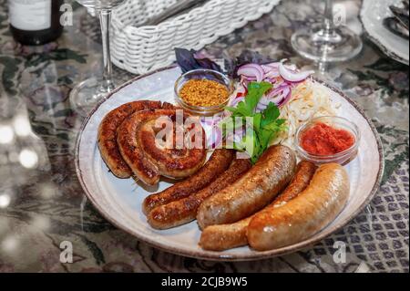 Das Restaurant serviert frische Würstchen und Hot Dogs, die auf dem Grill zubereitet werden. Nahaufnahme verschiedener Bratwürste Stockfoto