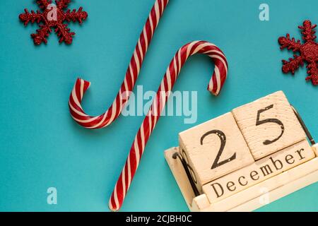 Holzblock Kalender zeigt 25. Dezember. Weihnachtsfeiertage. Grußkarte mit Zuckerstöcken und glitzernden Schneeflocken. Stockfoto