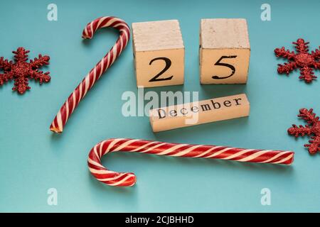 Holzblock Kalender zeigt 25. Dezember. Weihnachtsfeiertage. Grußkarte mit Zuckerstöcken und glitzernden Schneeflocken. Stockfoto
