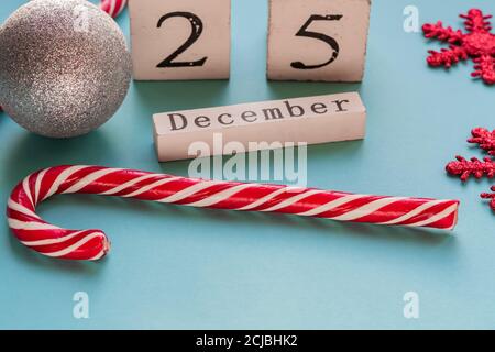 Holzblock Kalender zeigt 25. Dezember. Weihnachtsfeiertage. Grußkarte mit Zuckerstöcken und glitzernden Schneeflocken. Stockfoto