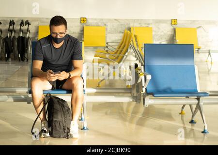 Kaukasischer Mann mit medizinischer Maske wartet auf seinen Flug in Ein Flughafen - neu normal nach Covid-19 Stockfoto