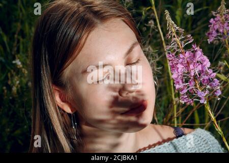 Hübsche junge Frau im Freien im Park mit Sommerblumen Stockfoto