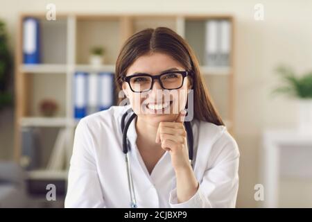 Porträt einer freundlichen jungen Ärztin am Schreibtisch im Büro Lächeln Sie geduldig Stockfoto