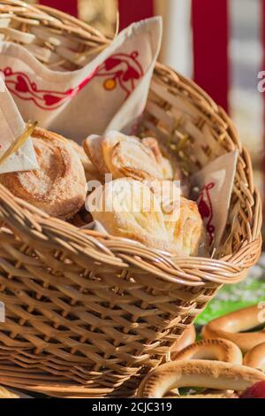 Leckere frische Brötchen im Weidenkorb, beleuchtet von der Sonne. Stockfoto