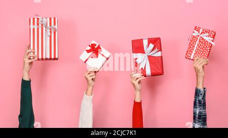 Hände halten und heben Geschenkschachteln in rosa isolierten Hintergrund Für Christmast- und Neujahr-Konzepte Stockfoto