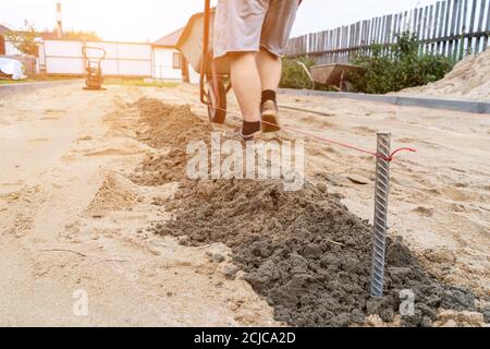 Ein Arbeiter bereitet eine Plattform für das Verlegen von Pflasterplatten im Defocus vor. Stockfoto