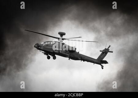 Der Hubschrauber der Armee apache fliegt weg, während er verstummelt wird Die Wolke von einer Explosion am Boden Stockfoto