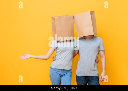 Konzeptuelle protrait von anonymen covered face paar halten sich gegenseitig Tun offene Handfläche Geste isoliert auf gelben Studio-Hintergrund Stockfoto